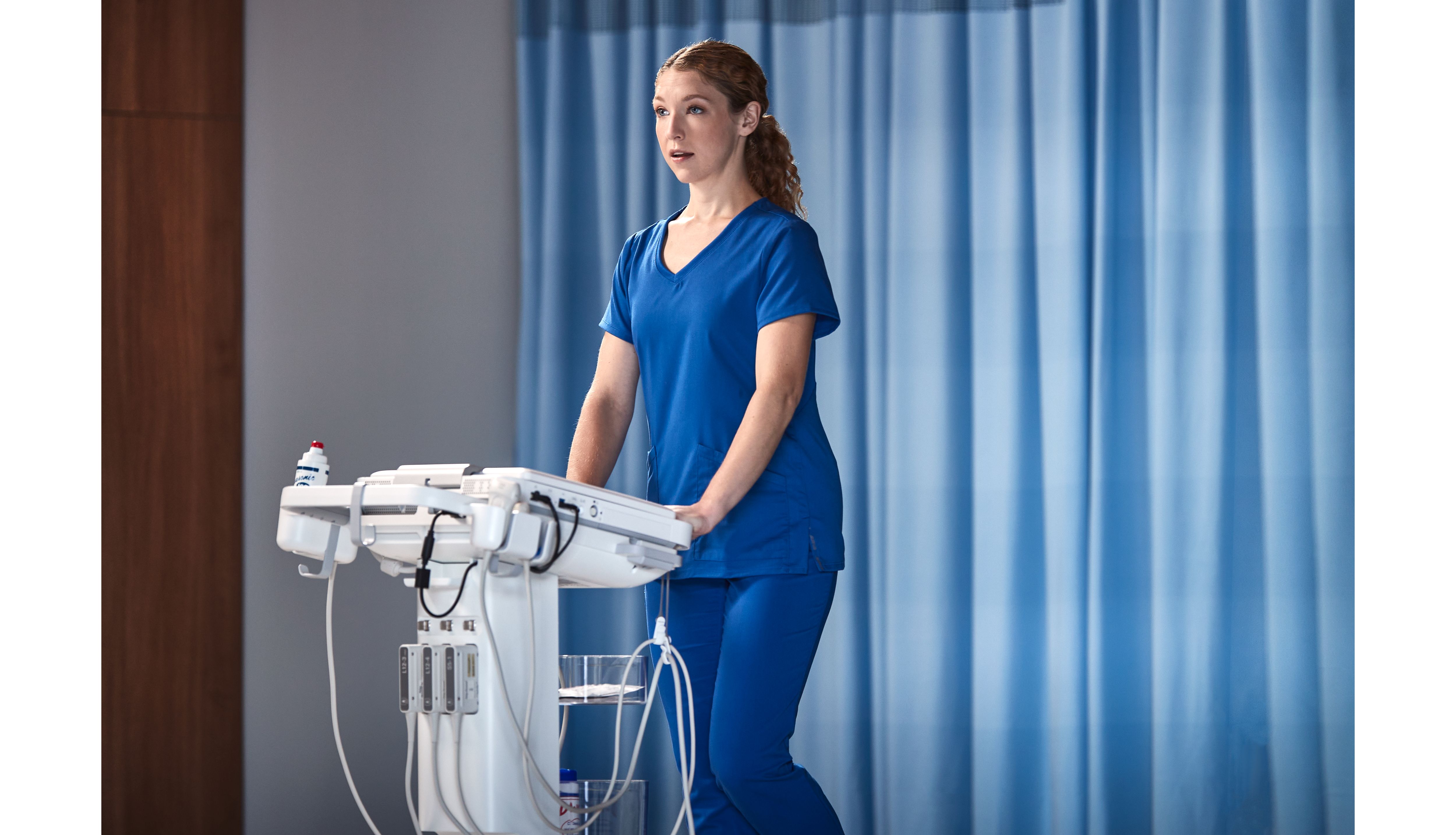 Photo of a female clinician remotely connecting with a specialist via teleultrasound from an ultrasound system while performing an ultrasound exam. 