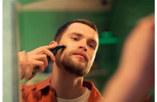 Ruskeahiuksinen ja -silmäinen mies käyttää Philips OneBlade -laitetta muotoillakseen pukinpartaa huulten yläpuolelta.